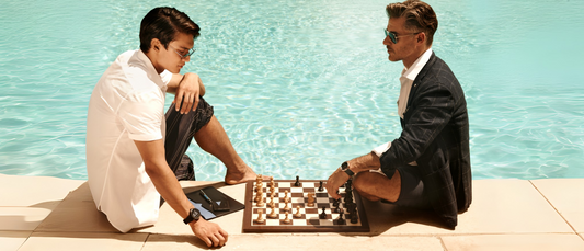 Two men playing chess by the poolside showcasing stylish Father's Day Gift Ideas for thoughtful and unique presents