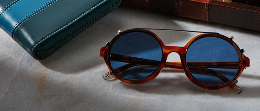 Top luxury sunglasses for women with round tortoiseshell frames and blue lenses next to a teal leather case